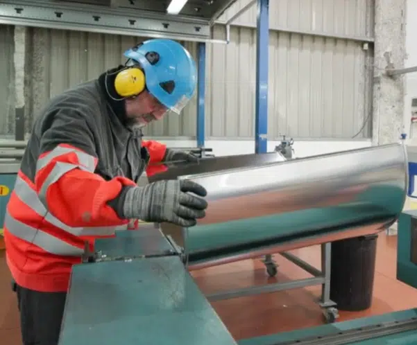 Operario fabricando revestimientos metálicos para aislamiento industrial en el taller automatizado de KAEFER en Asturias