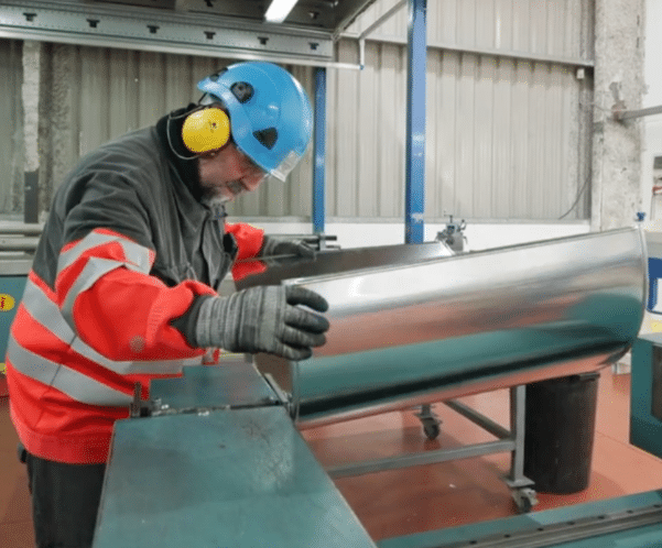 Operario fabricando revestimientos metálicos para aislamiento industrial en el taller automatizado de KAEFER en Asturias
